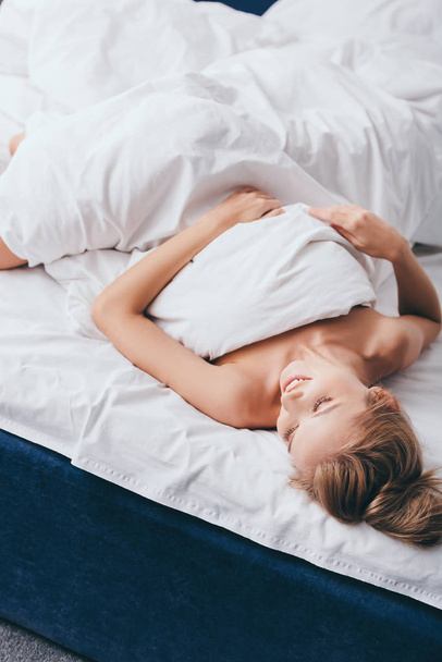 beautiful smiling woman lying in bed in morning - Photo, Image