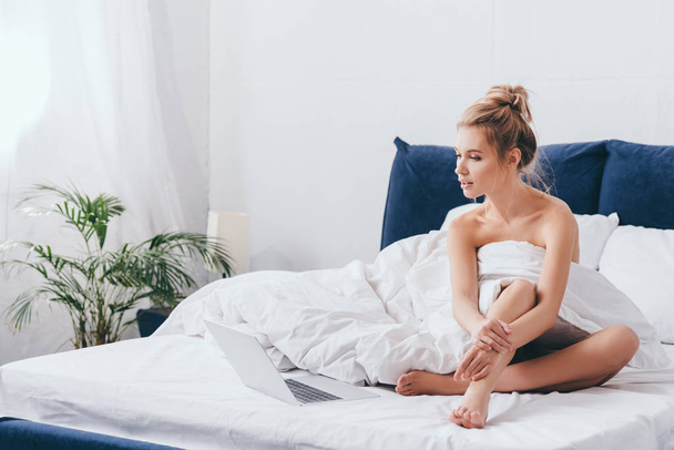 beautiful woman using laptop on bed with sheets in morning  - Photo, Image