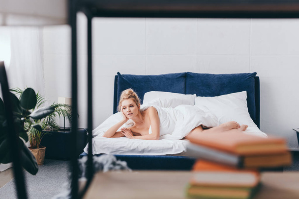 selective focus of attractive young woman lying in bedroom in morning - Fotó, kép