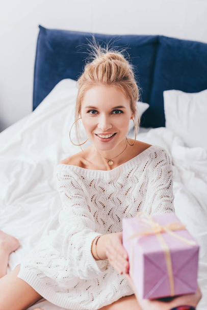 attractive happy woman taking gift box from man in bedroom - Foto, immagini