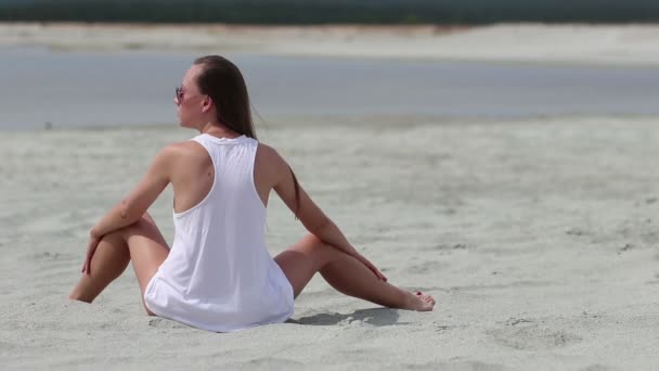 Mujer delgada sentada en posición de loto y alisando el cabello
 - Metraje, vídeo