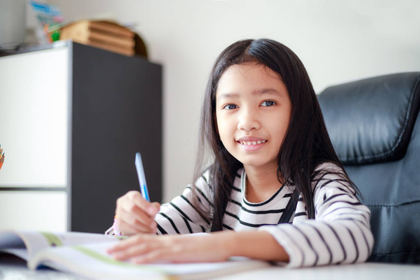 Sorria menina asiática fazendo lição de casa com felicidade para si mesmo l
 - Foto, Imagem