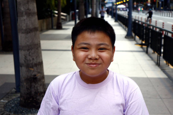 Jonge Filippijnse jongen poseren voor de camera, terwijl in een zakenwijk - Foto, afbeelding