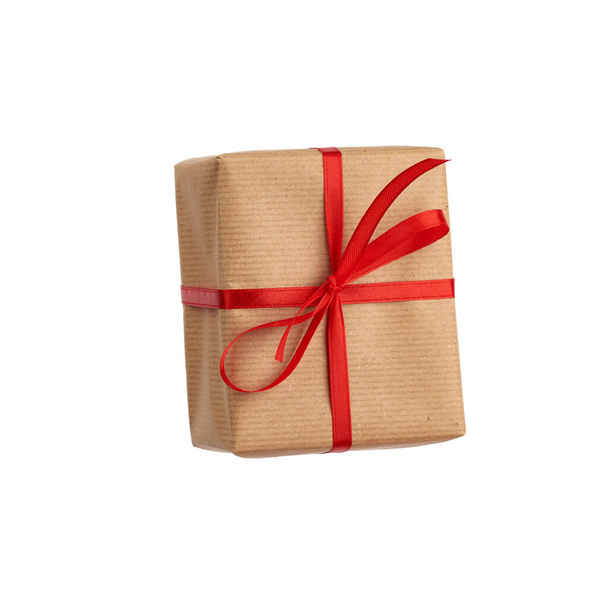 rechthoekige doos verpakt in bruin papier en gebonden met een rode strik,  - Foto, afbeelding