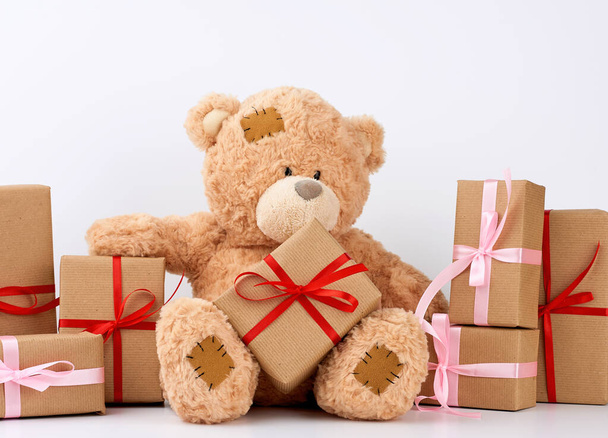 großer beiger Teddybär mit Aufnäher, ein Stapel Geschenke in Schachteln - Foto, Bild