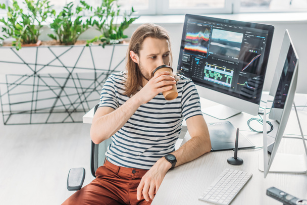 editor de arte mirando el monitor de la computadora mientras bebe café para ir
  - Foto, Imagen