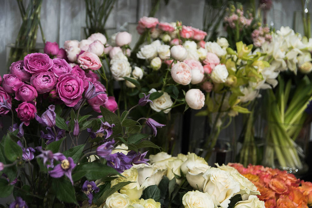Vitrine met vazen met verschillende gekleurde rozen, tulpen, pioenrozen in de bloemenwinkel. Prachtige lenteboeketten. Klein familiebedrijf. Werk bloemist - Foto, afbeelding