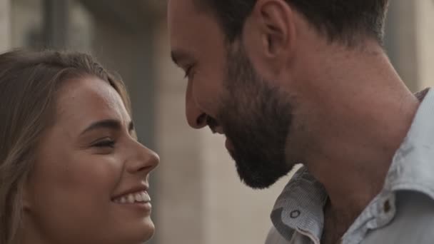 A close-up view of a lovely couple are looking at each other while standing at the city street - Video, Çekim