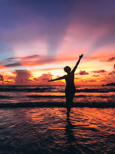 silueta de la hermosa mujer joven en la orilla del mar en la puesta del sol
 - Foto, imagen