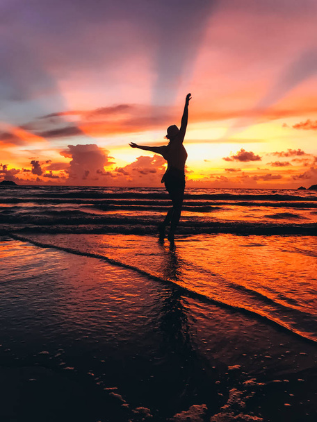 silhouette of beautiful young woman on seashore on sunset - Foto, imagen