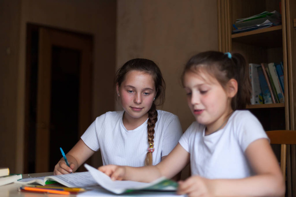 zwei Schwestern lernen Lektionen am Tisch. - Foto, Bild