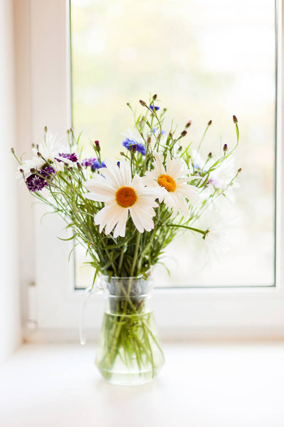 Bouquet of chamomiles and cornflowers in   vase on   table. - Photo, Image