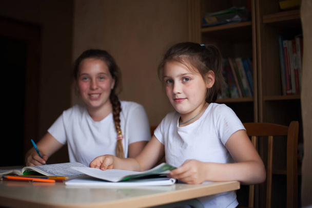  meisjes aan het bureau met notitieboekjes en boeken   - Foto, afbeelding