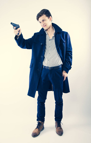An armed man wearing a coat, light background - Valokuva, kuva
