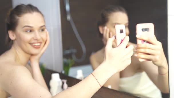 Hymyilevä nainen ottaen Mobile Selfie Photo Puhelimessa kylpyhuoneessa Mirror
. - Materiaali, video