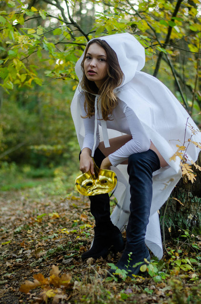 sexy young girl wearing white bodysuit and cloak posing in the forest - Foto, Imagen