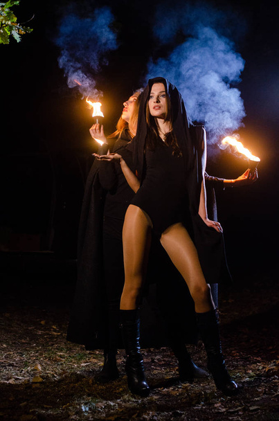 mistério meninas vestindo capas pretas, bruxa sábado na floresta à noite, perto da fogueira - Foto, Imagem