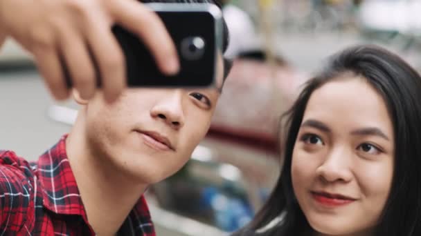 Handheld view of young Vietnamese couple making a selfie  - Materiał filmowy, wideo