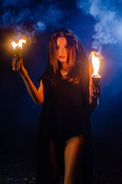 黒いマントを着た謎の少女たき火のそばの森の中の魔女の安息日 - 写真・画像