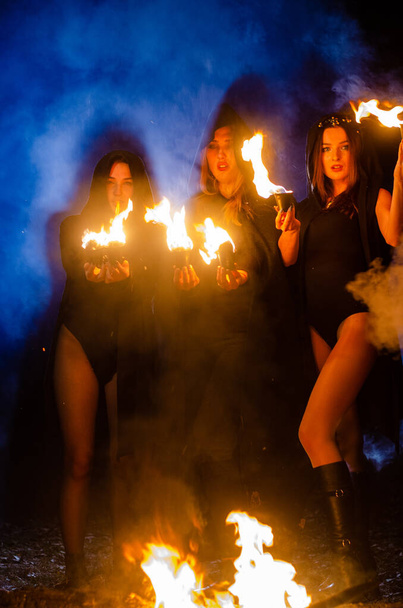 mistério meninas vestindo capas pretas, bruxa sábado na floresta à noite, perto da fogueira - Foto, Imagem