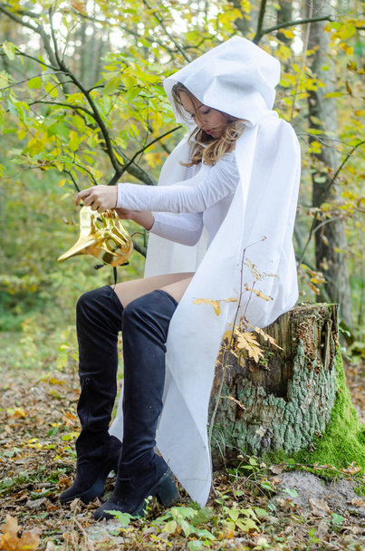 sexy joven con traje de cuerpo blanco y capa posando en el bosque - Foto, Imagen