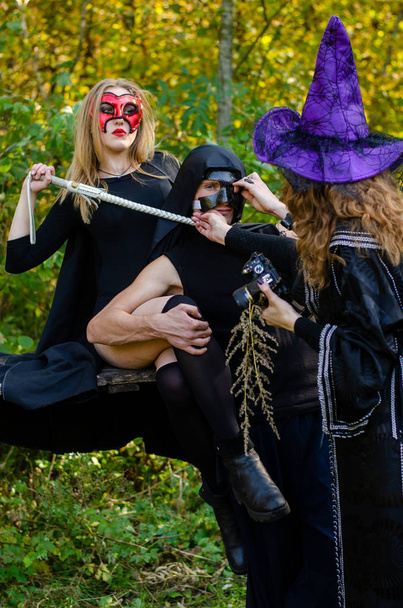 girls with the man wearing Halloween clothes in the forest - Photo, Image