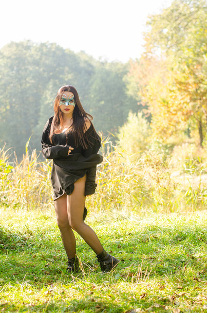 beautiful young woman in black carnival costume and mask posing on the woods - Φωτογραφία, εικόνα