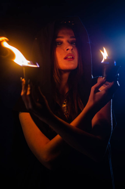 tajemnicza młoda dziewczyna w czarnym płaszczu, sabat wiedźmy w lesie w nocy przy ognisku - Zdjęcie, obraz