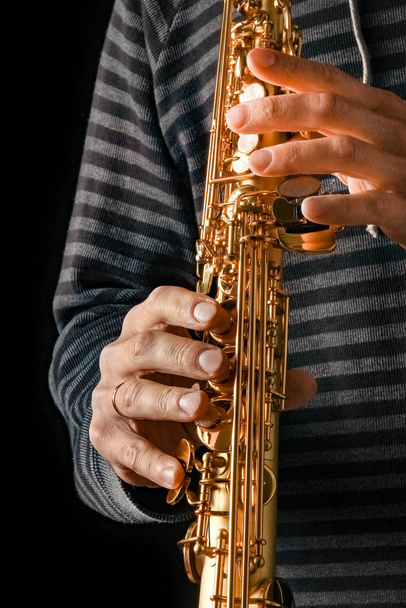 soprano saxophone in the hands of a guy on a black background - Фото, зображення