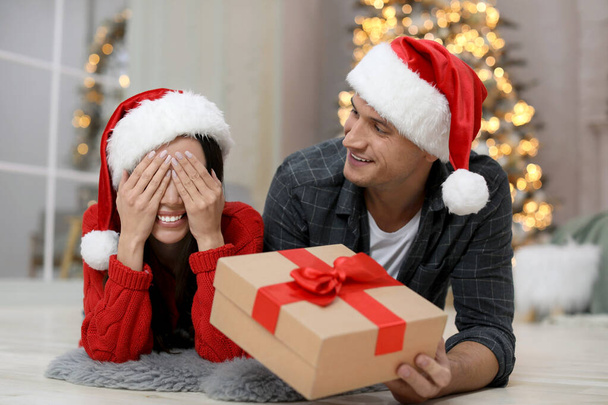 Man presenting Christmas gift to his girlfriend at home - Fotó, kép