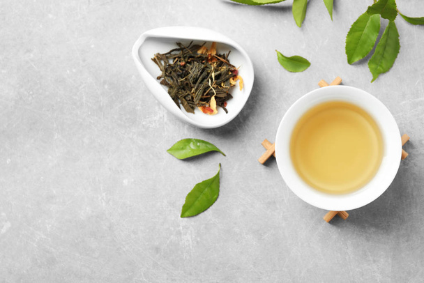 Cup of green tea, dry and fresh leaves on grey table, flat lay. Space for text - Photo, Image