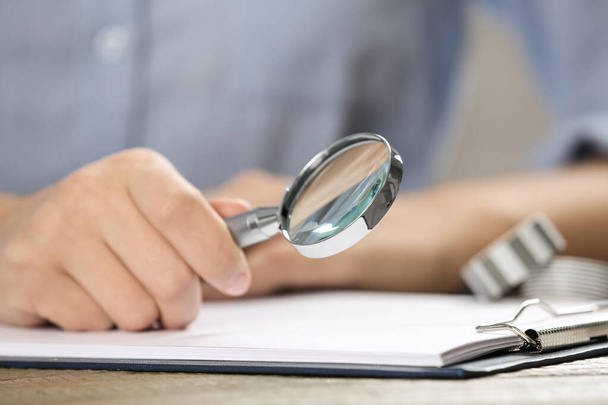 Woman using magnifying glass at table, closeup - Foto, immagini