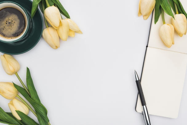 horní pohled na tulipány, prázdný zápisník s perem a čerstvou kávu izolovanou na bílém - Fotografie, Obrázek