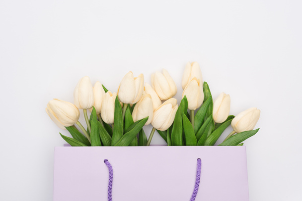 top view of tulips in violet shopping bag isolated on white - 写真・画像