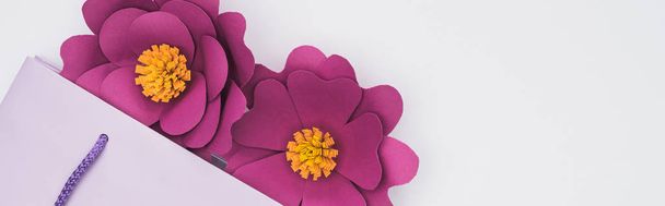 top view of paper cut flowers in violet shopping bag isolated on white, panoramic shot - Photo, Image