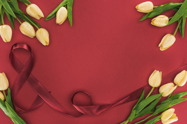 vrchní pohled na tulipány s hedvábnou stuhou izolované na červené s kopírovacím prostorem - Fotografie, Obrázek