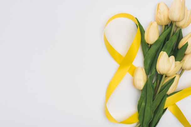 vista superior de tulipanes y número 8 hecha de cinta amarilla aislada en blanco
 - Foto, Imagen