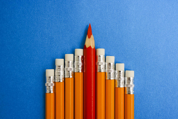 one red  Big Pencil Color rises above the rest yellow pencils. isolated on blue background.  - Foto, imagen