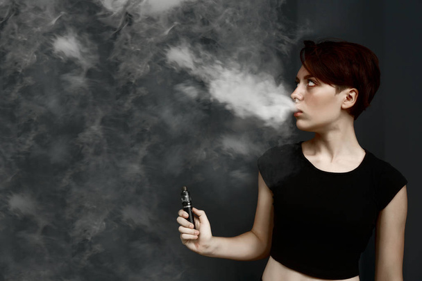 young girl smoking  electronic cigarette. female model vaping a vaporizer  - Fotó, kép