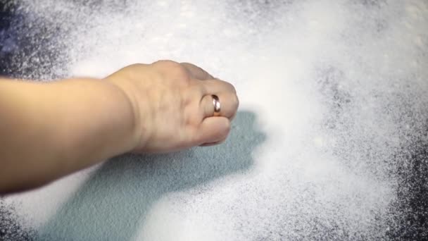 Flour is sprinkled on the table. They draw a heart on it with a finger. Valentine's Day. Dark marbled background. White flour. - Materiaali, video