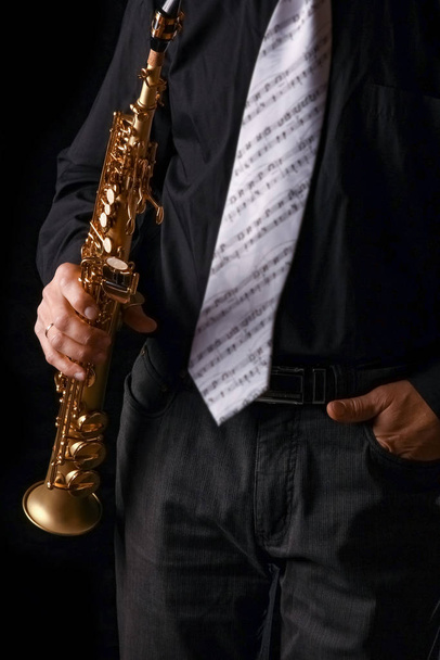 soprano saxophone in the hands of a guy on a black background - Photo, image