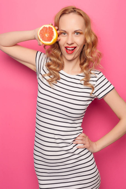 Funny young girl with halfs of fresh ripe grapefruit orange - Foto, afbeelding
