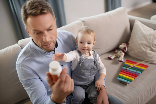 Good-looking father looking attentive reading about vitamins - Foto, Imagen