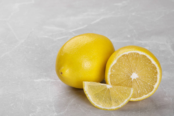 Whole and cut fresh ripe lemons on grey marble table - Photo, Image
