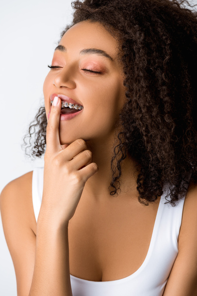 chica afroamericana soñadora con frenos dentales, aislada en gris
 - Foto, Imagen