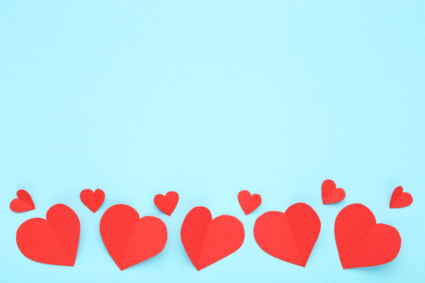 Red paper hearts on blue background - 写真・画像