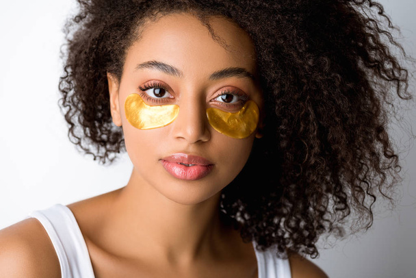 красива кучерява афроамериканська дівчина з золотими плямами очей, ізольована на сірому
 - Фото, зображення