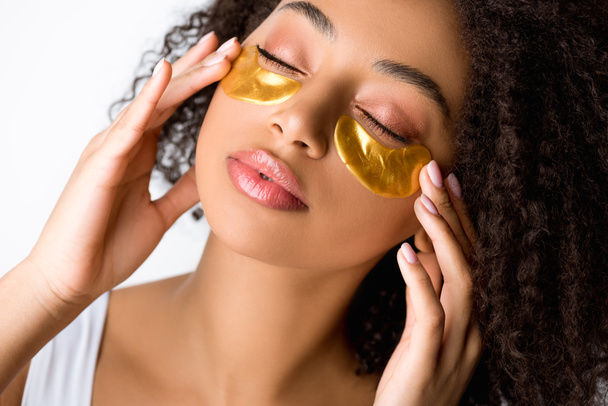 atrakcyjna Afroamerykanka ze złotymi przepaskami na oczy i zamkniętymi oczami, odizolowana na szaro - Zdjęcie, obraz