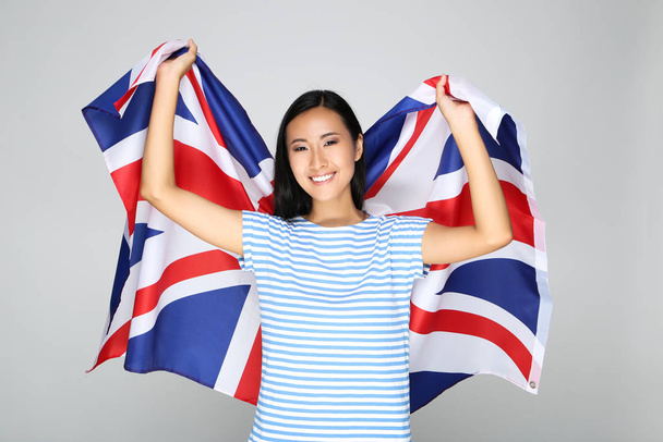 Young woman holding British flag on grey background - Fotografie, Obrázek