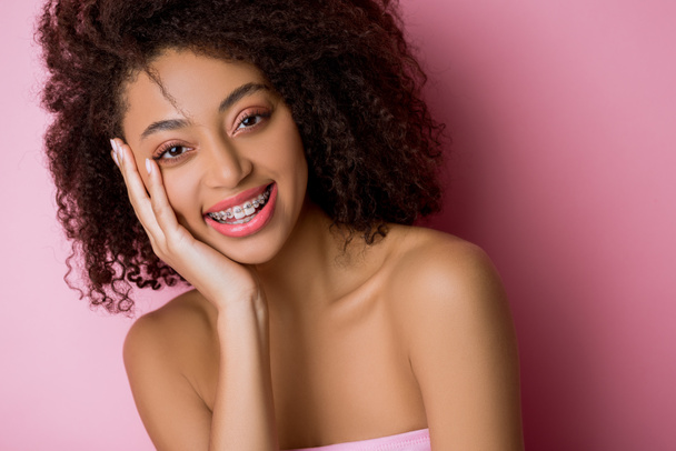 beautiful happy african american girl with dental braces on pink - Photo, Image